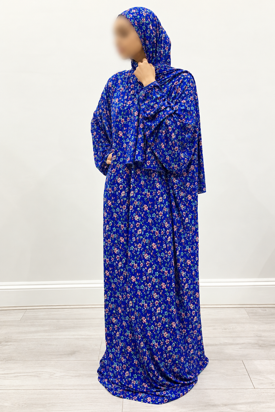 Three-quarter view of royal blue floral prayer dress with small pink flowers, attached hijab and plain, lace-free edges