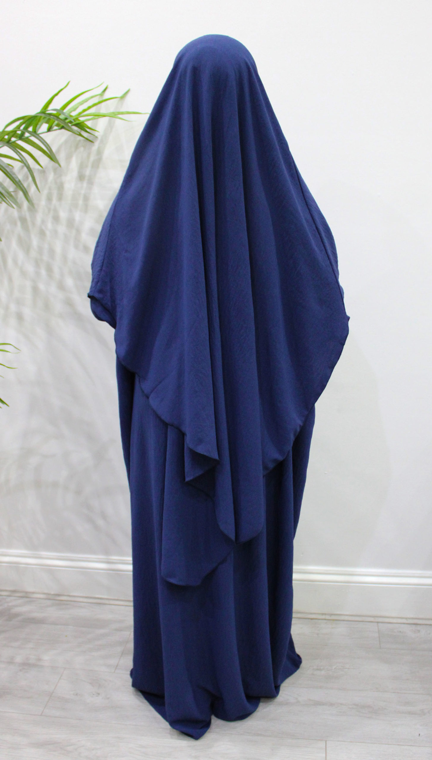  A navy blue abaya and matching khimar set made from soft crepe fabric, featuring a loose-fit abaya and a long diamond-shaped khimar with adjustable straps.